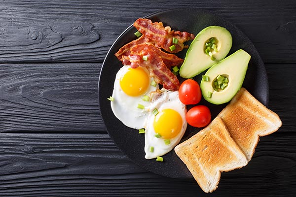 Aguacate, dos huevos fritos, varias lonchas de bacon, tomates cherry y un par de tostadas de pan