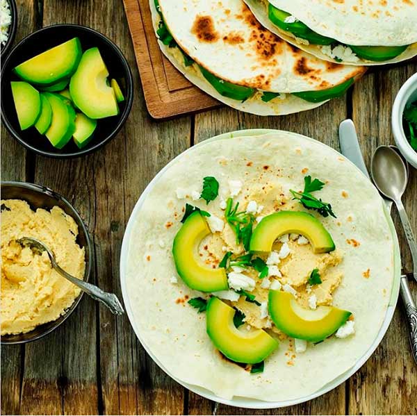 Tortillitas de maíz con rodajas de aguacate, un poco de hummus, queso feta y perejil fresco